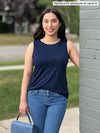 Woman standing next to a building wearing Miik's Shandra reversible tank top in navy with jeans.
color_navy