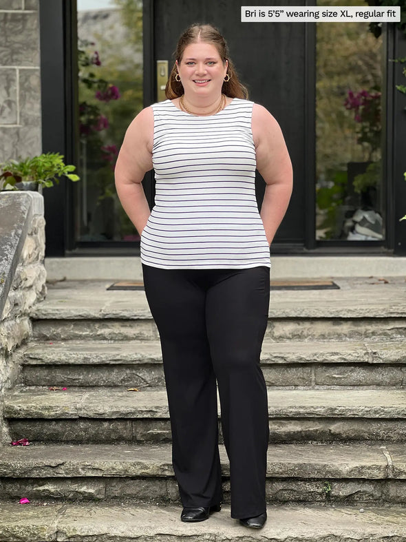 Miik model Bri ('5", xlarge) smiling wearing a wide leg pant in black with Miik's Shandra reversible neckline tank top in newport stripe #color_newport-stripe