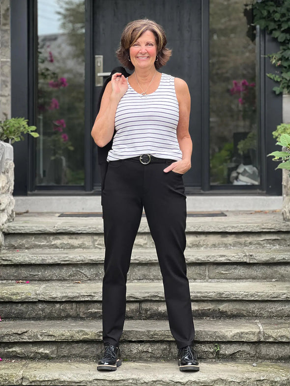 Miik founder Donna (5'6", small) smiling wearing Miik's Shandra reversible neckline tank top in newport stripe with a black dress pant and belt 
