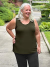 Miik model Colleen (5'3", xxlarge) smiling and looking away wearing Miik's Shandra reversible tank top in olive with a charcoal dress pant 
#color_olive