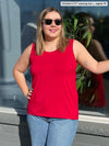 Miik model Christal (5'3, large) smiling and looking away wearing Miik's Shandra reversible tank top in poppy red with jeans and sunglasses
#color_poppy-red 