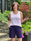 Miik founder Donna (5'6", small) smiling wearing Miik's Shandra reversible tank top in sunrise stripe with a purple bermuda short 