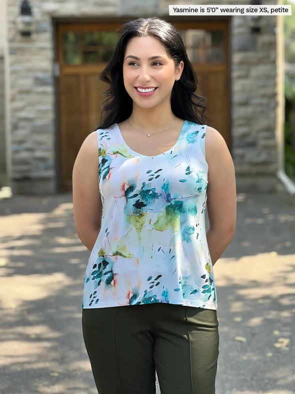 Miik model Yasmine (5'0", xsmall, petite) smiling and looking away wearing Miik's Shandra reversible tank top in water lily in the petite fit along with a dress pant in olive green 
#color_water-lily