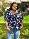 Miik model plus size Kimesha (58", 3x) smiling wearing Miik's Shanice flutter sleeve square neck t-shirt in blossom print with jeans 