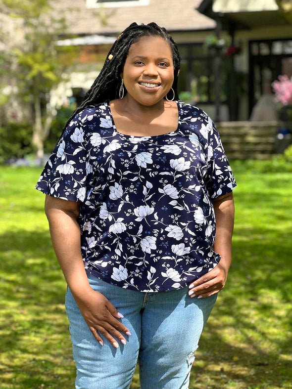 Miik model plus size Kimesha (58", 3x) smiling wearing Miik's Shanice flutter sleeve square neck t-shirt in blossom print with jeans