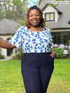 Miik model plus size Erica (5'8", 2x) smiling wearing a dress pant in navy along with Miik's Shanice flutter sleeve square neck t-shirt in ink leaf 