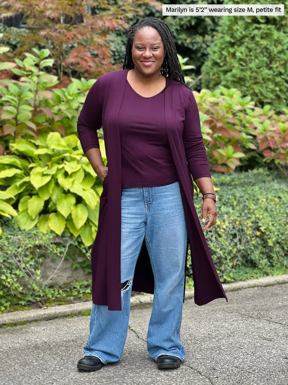 Miik model Marilyn (5'2. medium) smiling wearing Miik's Shannon reversible neckline long sleeve tee in port, petite fit, along with a duster cardigan in the same colour and jeans #color_port 