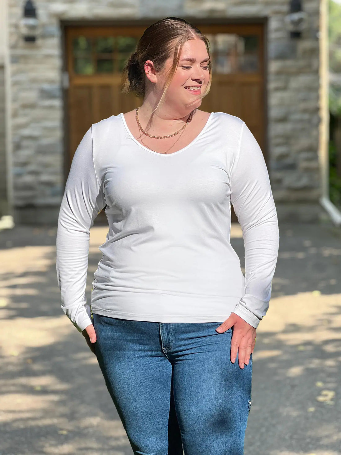 Miik model Bri (size XL) is wearing the Shannon long sleeve reversible t-shirt in white with blue jeans 