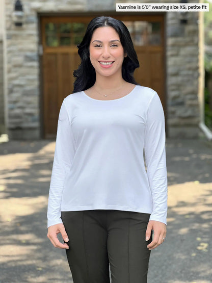 Miik model Yasmine (size XS) wearing the Shannon reversible long sleeve t-shirt in white, petite fit, with olive pants. She is wearing the round neckline side in the front, and the v-neck in the back. 