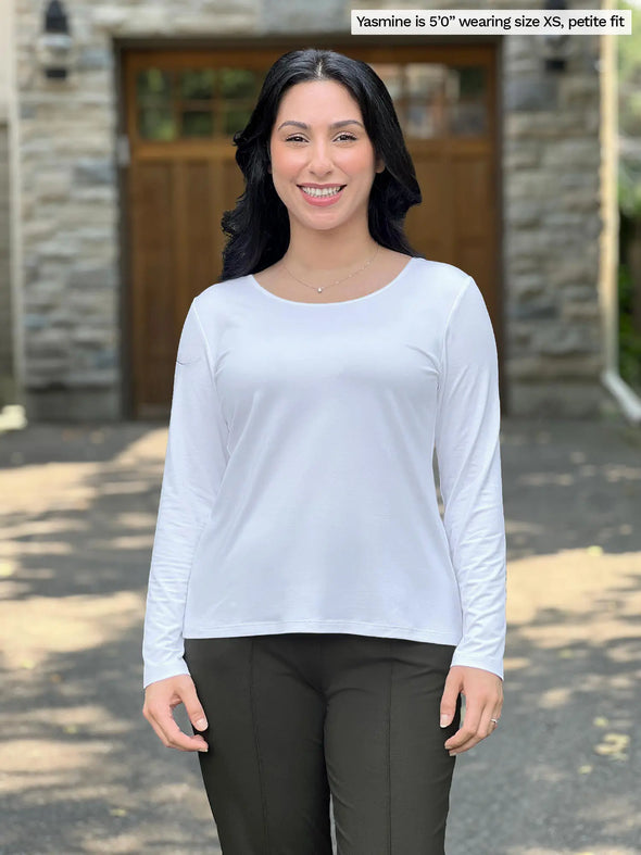 Miik model Yasmine (size XS) wearing the Shannon reversible long sleeve t-shirt in white, petite fit, with olive pants. She is wearing the round neckline side in the front, and the v-neck in the back. #color_white