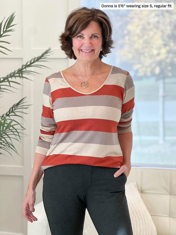 Miik founder Donna (5'6", small) smiling wearing Miik's Shannon reversible neckline long sleeve tee in sedona stripe with a charcoal dress pant #color_sedona-stripe