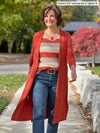 Miik founder Donna (5'6", small) smiling and looking away wearing Miik's Shannon reversible neckline long sleeve tee in sedona stripe with a duster cardigan in paprika melange and jeans #color_sedona-stripe