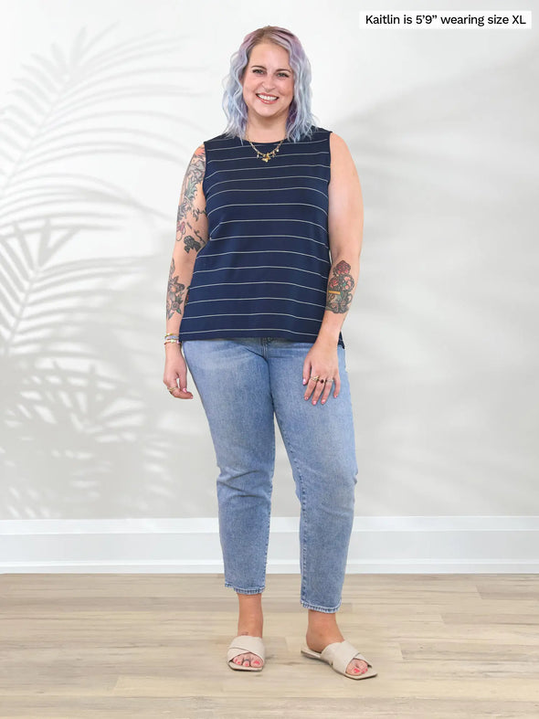 Miik model Kaitlin (5'9", xxlarge) smiling wearing Miik's Shyanne reversible neckline side slit tank in navy pinstripe with jeans #color_navy-pinstripe 