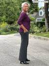 Miik model Keethai (5'5", medium) smiling while standing sideway showing the detail of the pockets of the Miik's Sierra high waisted pocket pant in charcoal #color_charcoal 