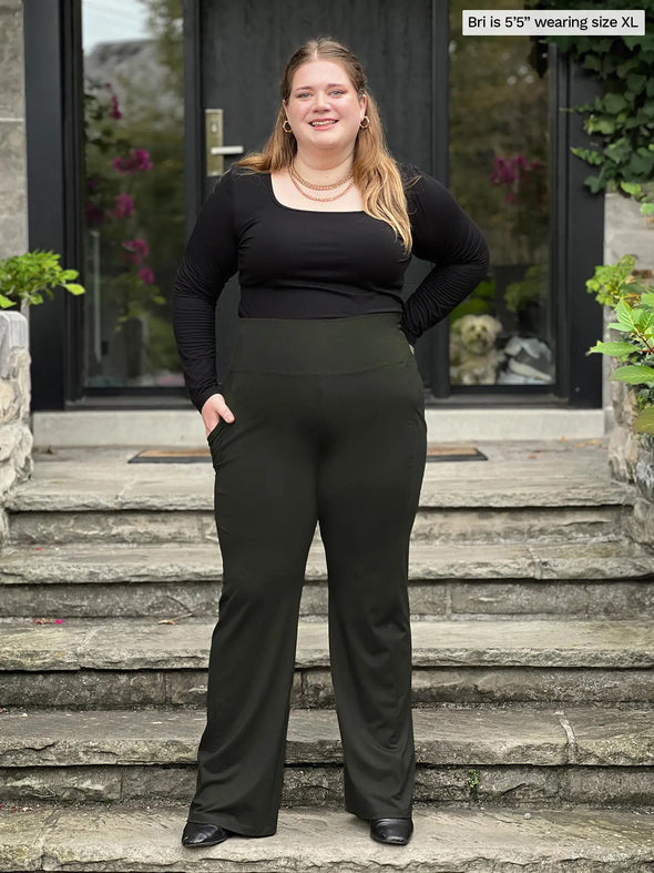 Miik model Bri (5'5", xlarge) smiling wearing Miik's Sierra high waisted pocket pant in olive with a square neck long sleeve top in black #color_olive 