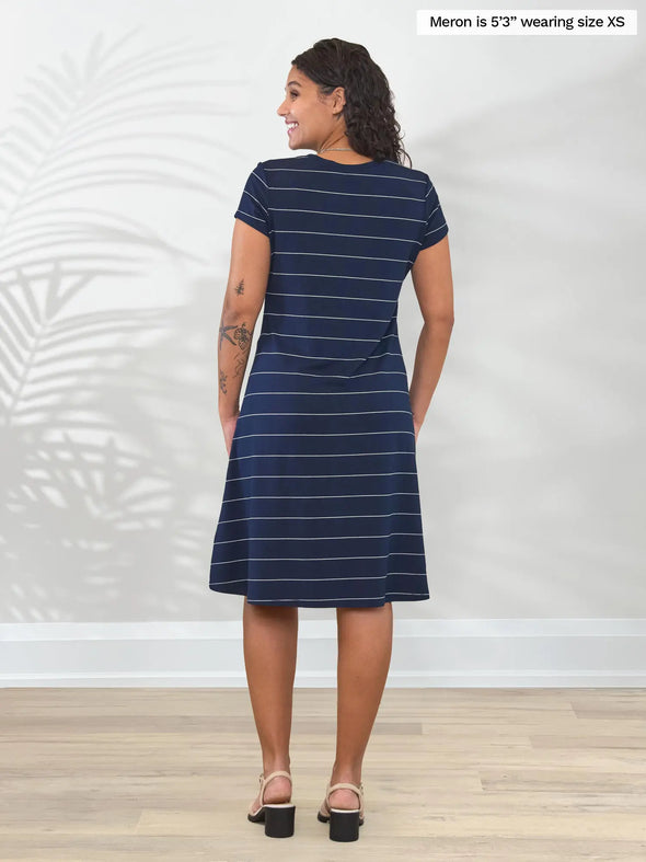 Miik model Meron (5’3”, xsmall) standing with her back towards the camera showing the back of Miik's Silas t-shirt dress with pockets in navy pinstripe #color_navy-pinstripe 