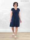 Miik founder Donna (5'6", small) smiling while standing in front of a white wall wearing a white flip flop sandals with  Miik's Silas t-shirt dress with pockets in navy pinstripe #color_navy-pinstripe 