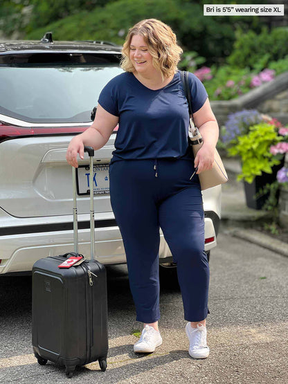 Miik model Bri (size XL, 5 foot 5) wearing the Stef open-back jumpsuit as she gets ready to put a travel suitcase in her car for a trip 