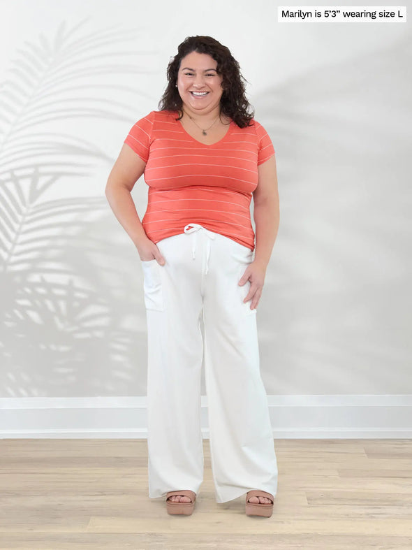 Miik model Marilyn (5'3", large) smiling wearing Miik's Sutton v-neck classic tee in papaya wide pinstripe with a natural lounge pants #color_papaya-wide-pinstripe 