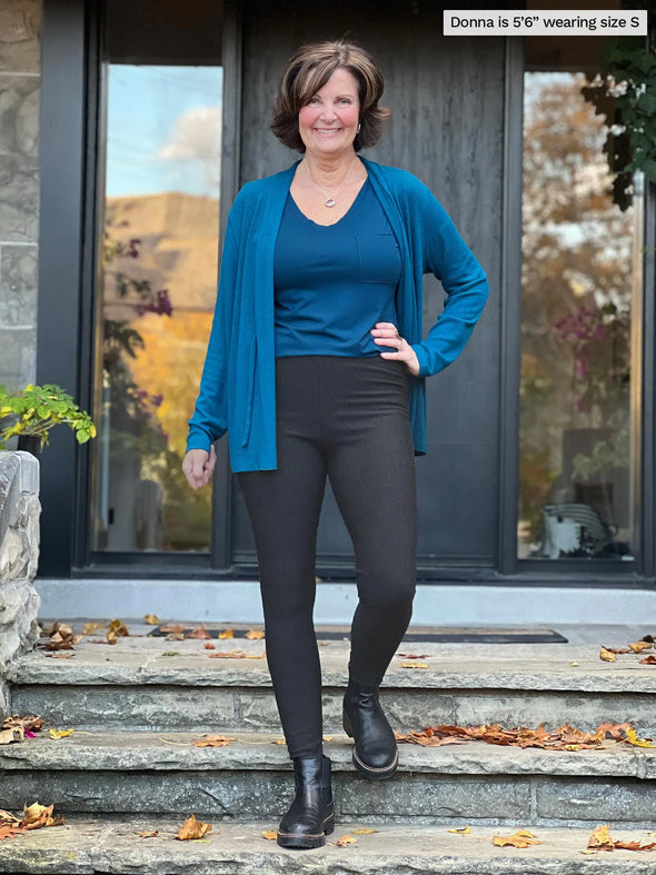 Miik founder Donna (5'6", small) smiling wearing Miik's Tinsley mid-rise fleece legging in charcoal along with a pocket tee in teal and a fleece cardigan in teal melange #color_charcoal 