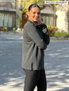 Miik model Meron (5'3", xsmall) standing sideway wearing Miik's Tristan 1/4 zip fleece pullover in charcoal with black leggings #color_charcoal 