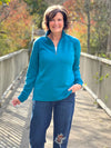 Miik founder Donna (5'6", small) smiling wearing Miik's Tristan 1/4 zip fleece pullover in teal melange with a ripped jeans #color_teal-melange 