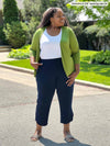 Miik model Kimesha (5'8", 3x) looking away wearing a capri pant in navy, a white tank and Miik's Wesley cropped cardigan in green moss