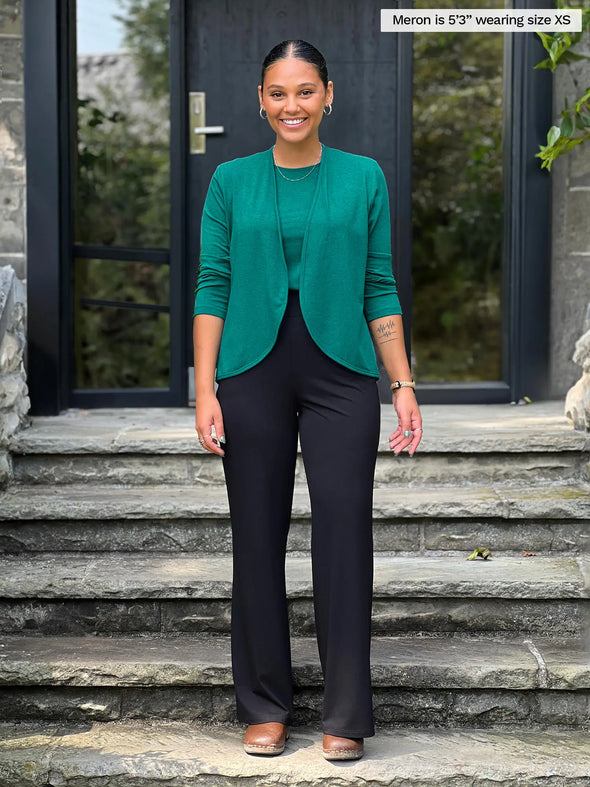 Miik model Meron (5'3", xsmall) smiling wearing Miik's Wesley cropped cardigan in jade melange along with a tank top in the same colour and a black pant 
#color_jade-melange 