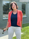 Miik founder Donna (5'6, small) smiling wearing Miik's Wesley cropped cardigan in papaya with a navy tank top and white jeans 