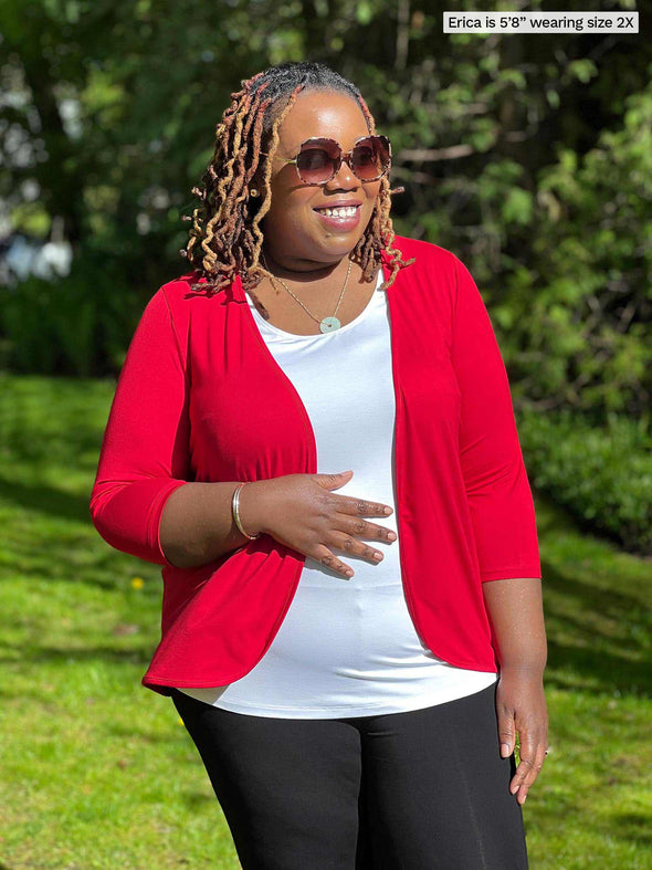 Miik model plus size Erica (5'8", 2x) smiling wearing Miik's Wesley cropped cardigan in poppy red with a white tank and black leggings 