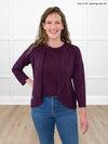 Miik model Lex (5'2", xsmall) smiling wearing Miik's Wesley cropped cardigan in port with a tank top in the same colour and jeans 
#color_port