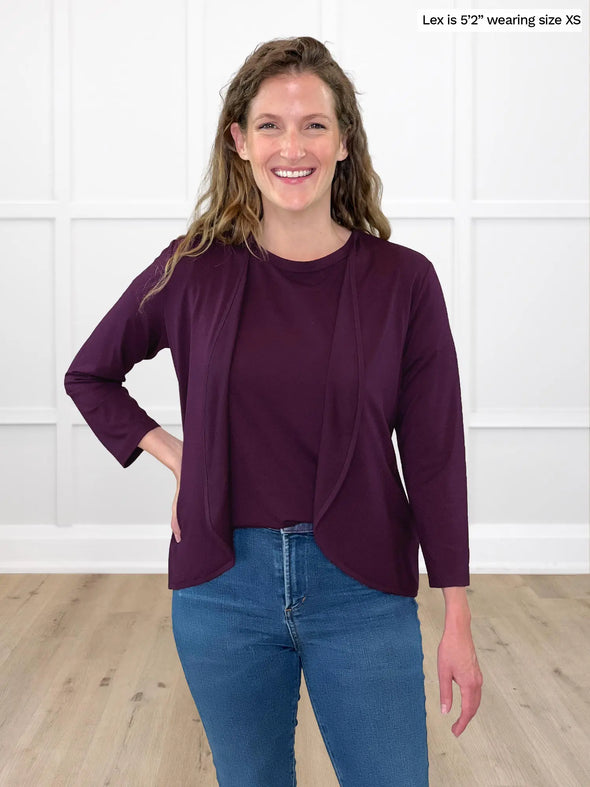 Miik model Lex (5'2", xsmall) smiling wearing Miik's Wesley cropped cardigan in port with a tank top in the same colour and jeans 
#color_port