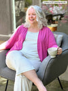 Woman sitting wearing Miik's Wesley cropped cardigan in pink over her pjs.