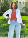 Miik model Meron (5'3", xsmall) smiling wearing Miik's Wesley cropped cardigan in white with a paprika melange tank and jeans 
#color_white