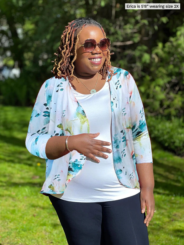 Miik model Erica (5'8", 2x, plus size) smiling and looking away wearing Miik's Wesley cropped cardigan in water lily print along with a white tank and navy pant 
#color_water-lily