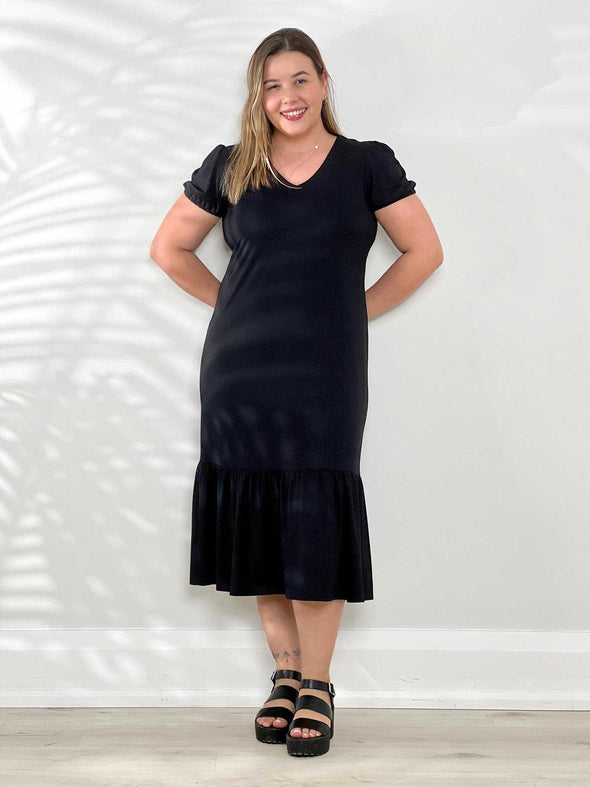 Miik model Christal (5'3", medium) smiling wearing Miik's Zilma reversible puff sleeve midi dress in black #color_black