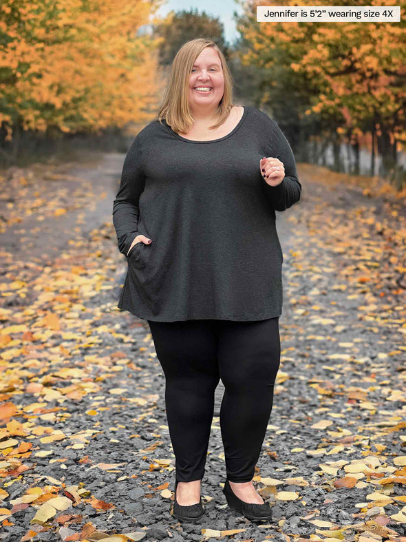 Miik model plus size Jen (5'2", size 4x) smiling wearing a black legging along with Miik's Zuri long sleeve pocket tunic in charcoal with a high waited legging in black #color_charcoal