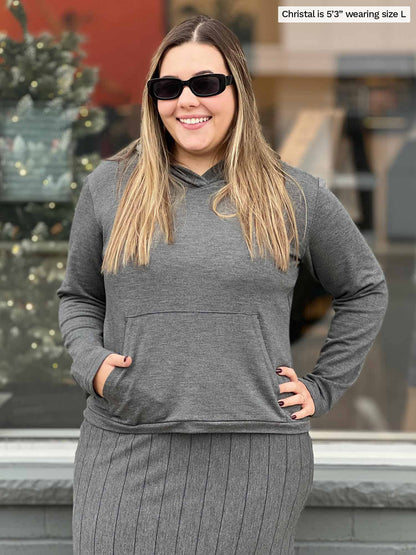 Woman smiling standing in front of a window wearing Miik&