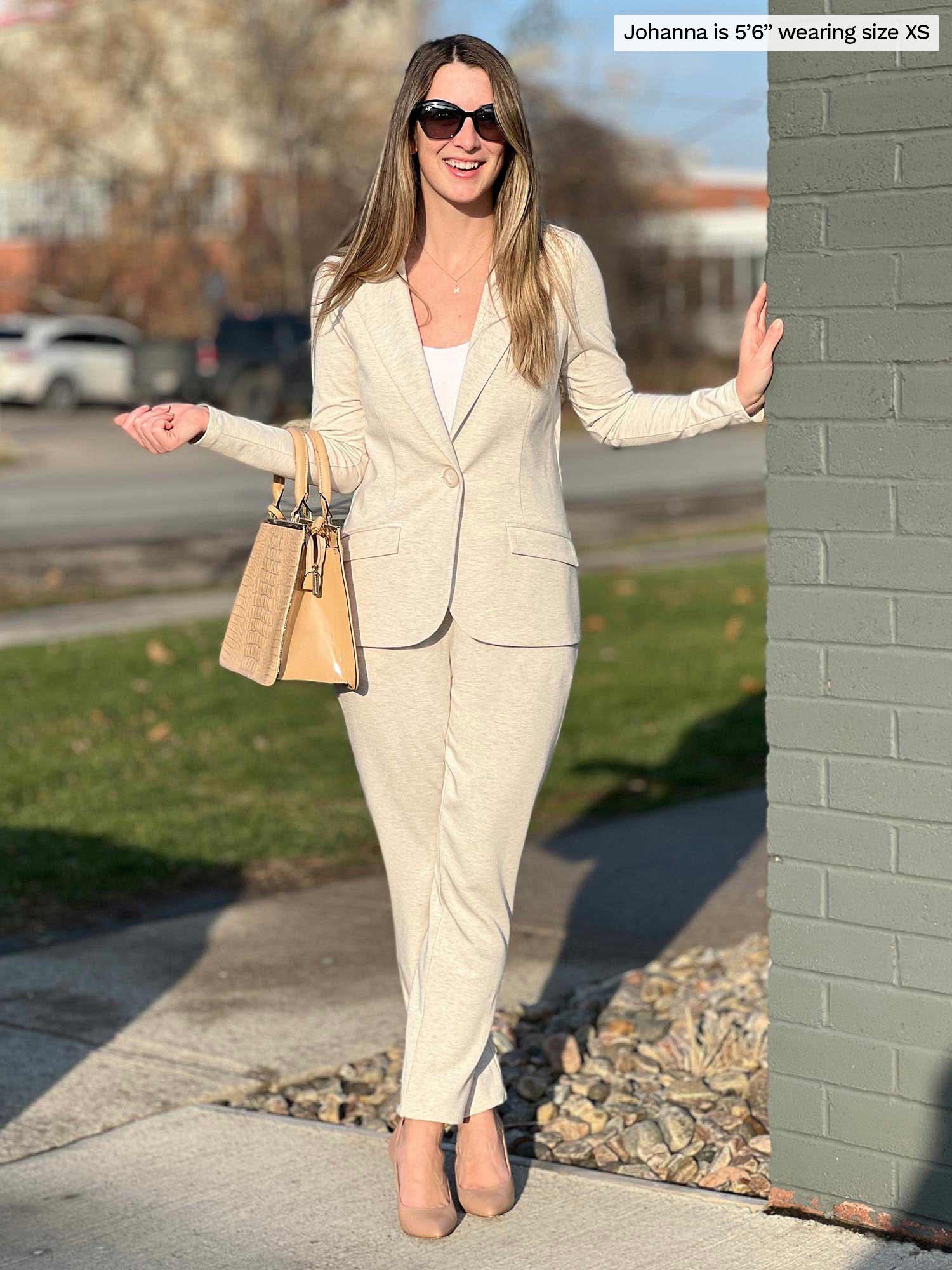 Woman standing next to a brick wall wearing a blazer in oatmeal melange along with Miik&