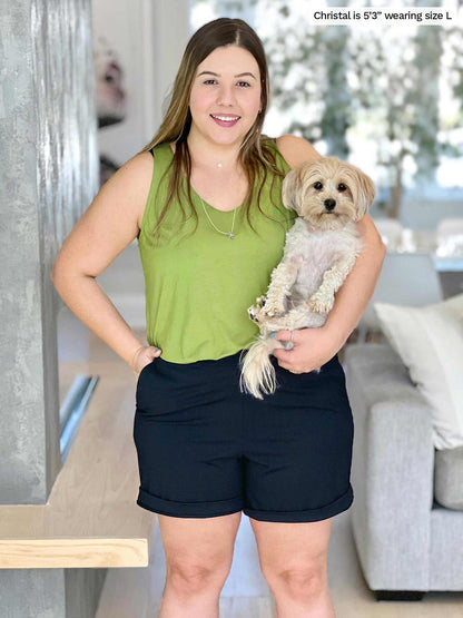 Miik model Christal (five feet three, size large) smiling while holding a puppy and hands on pockets wearing Miik&