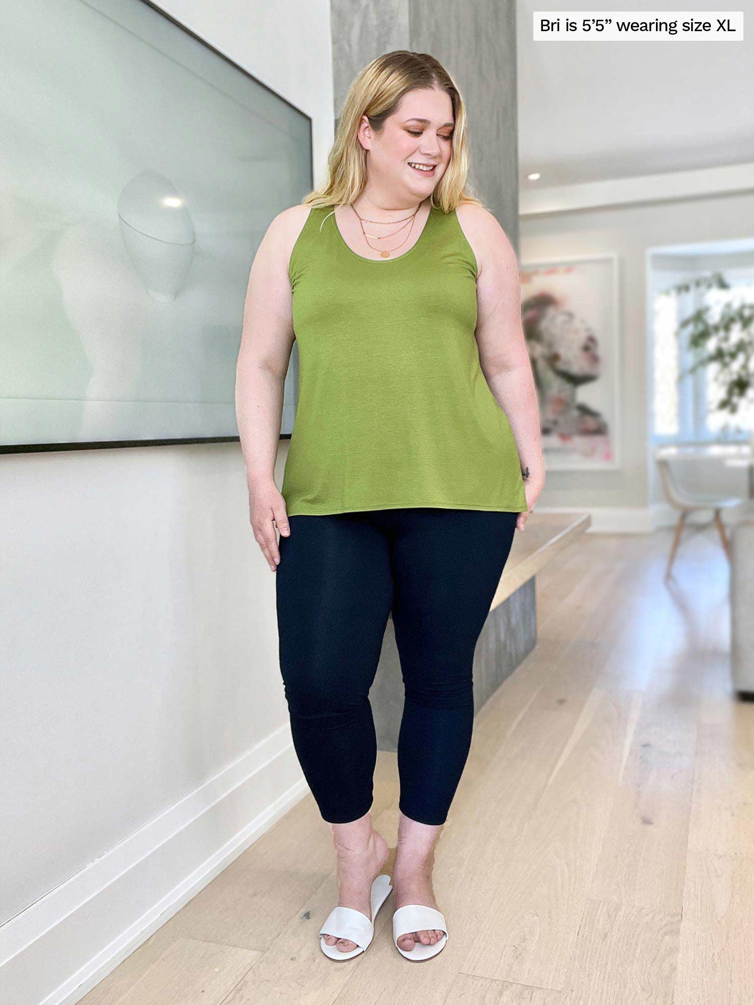 Miik model Bri (five feet five, size extra large) standing in a living room and looking down wearing a capri legging with Miik&